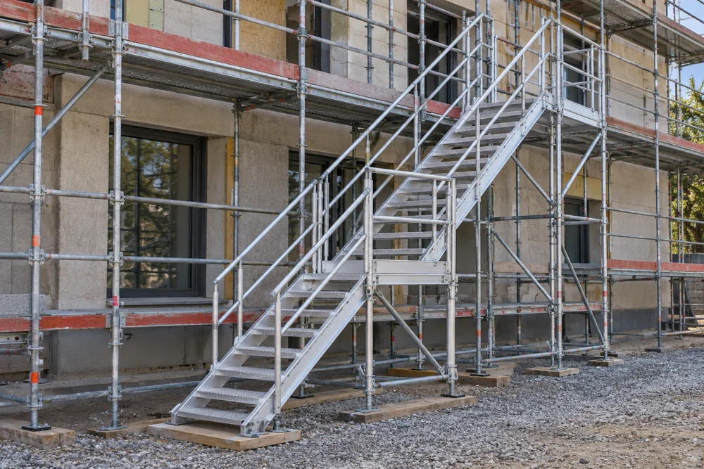 Aluminium stair tower beside the scaffolding with handrails and intermediate landings